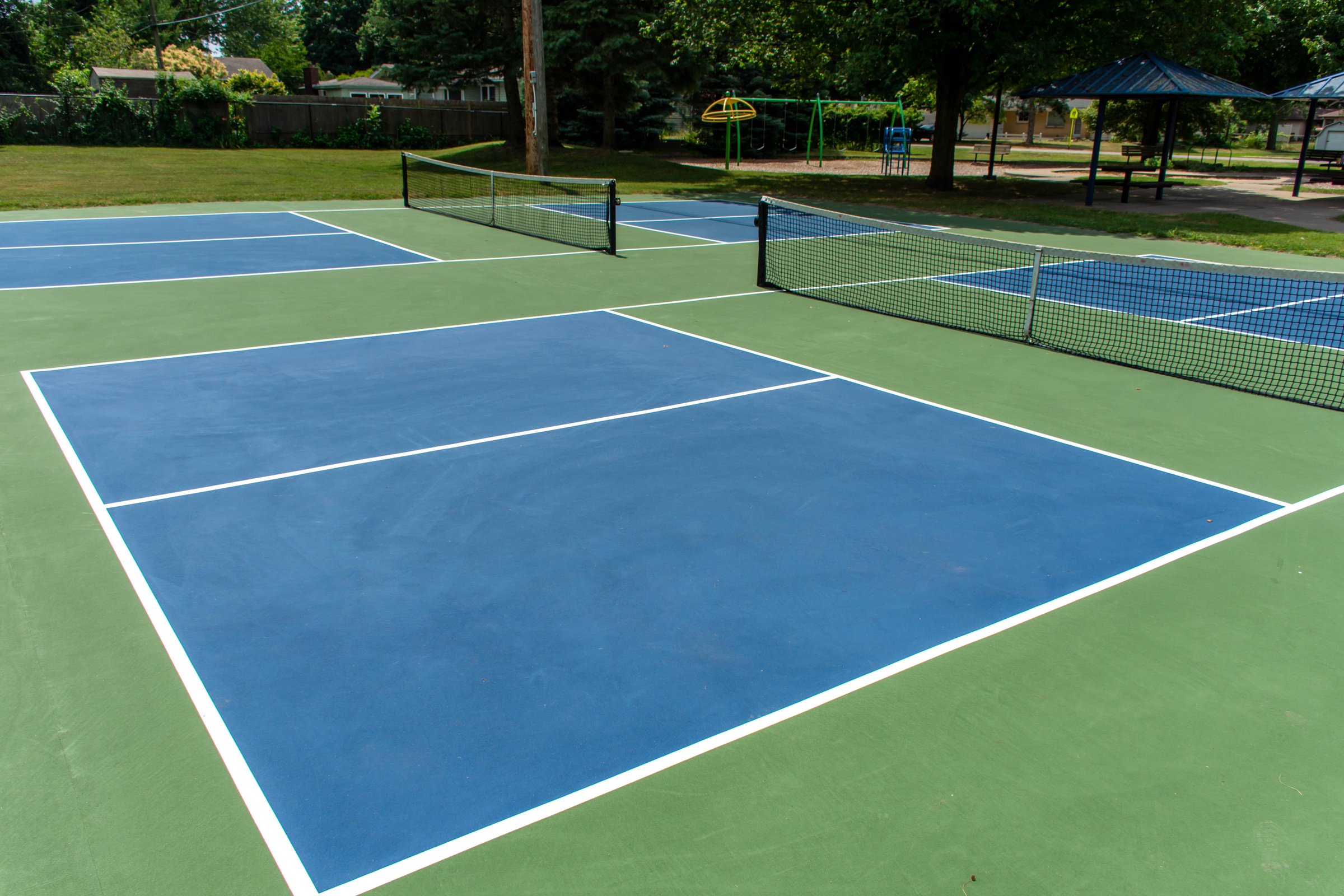 Recreational sport of pickleball court in Michigan, USA looking at an empty blue and green new court at a outdoor park.